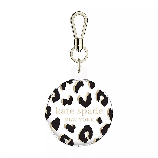 The image features a Kate Spade New York keychain with a leopard print design. The keychain is round and has a gold clasp. The Kate Spade logo is prominently displayed on the keychain, making it a stylish and functional accessory for the user.