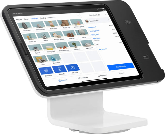 The image displays a tablet computer sitting on a stand. The tablet is turned on and shows a screen with several photos displayed. The photos are arranged in a grid-like pattern, with each photo occupying a square on the screen. The tablet is positioned at a slight angle, making it easy to view the photos.